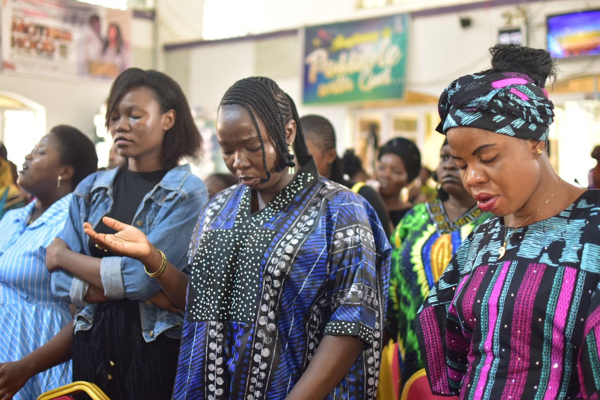 Women praying fervently with eyes closed and hands raised