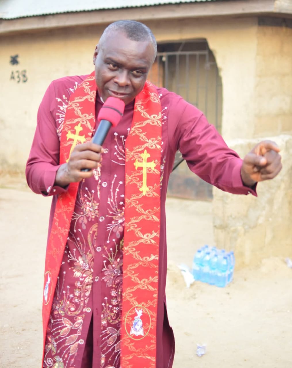 Apostle Prof. E. C. Ejiofor at the pulpit holding a pencil as an object lesson while preaching at Praiseland Royal Springs Int'l Church