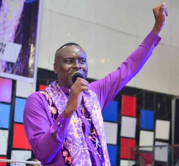 Apostle Prof. E. C. Ejiofor preaching in a purple robe with a decorative stole at Praiseland Royal Springs Int'l Church